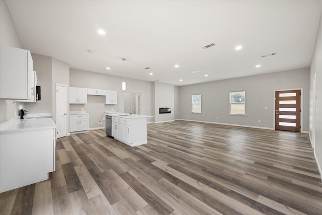 kitchen featuring hardwood / wood-style flooring, a kitchen island with sink, sink, and white cabinets