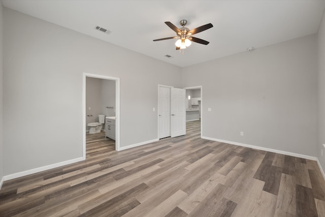 unfurnished bedroom with wood-type flooring, connected bathroom, and ceiling fan