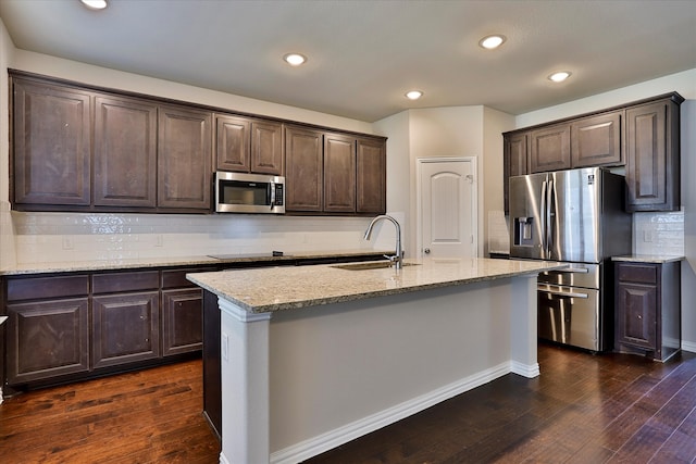 kitchen with sink, stainless steel appliances, dark hardwood / wood-style floors, decorative backsplash, and a center island with sink