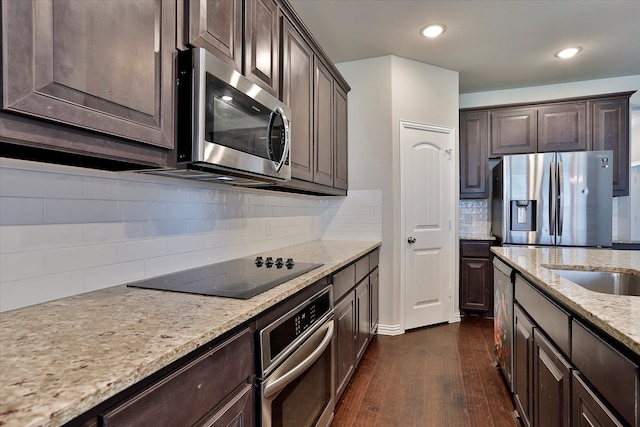 kitchen with decorative backsplash, dark wood-type flooring, stainless steel appliances, dark brown cabinets, and light stone countertops