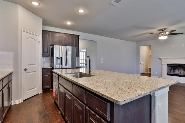 kitchen with dark hardwood / wood-style flooring, appliances with stainless steel finishes, a kitchen island with sink, dark brown cabinetry, and sink