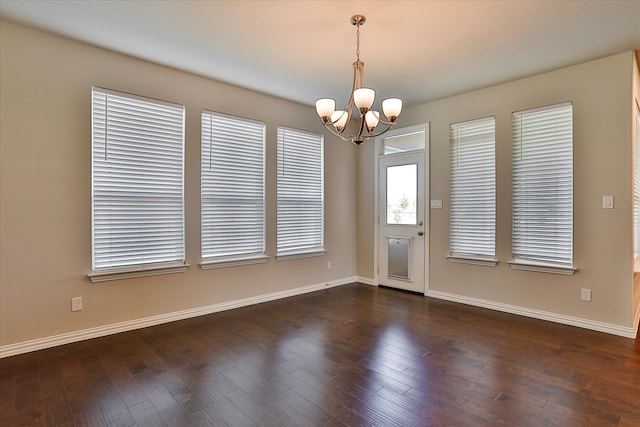 empty room with a chandelier and dark hardwood / wood-style flooring