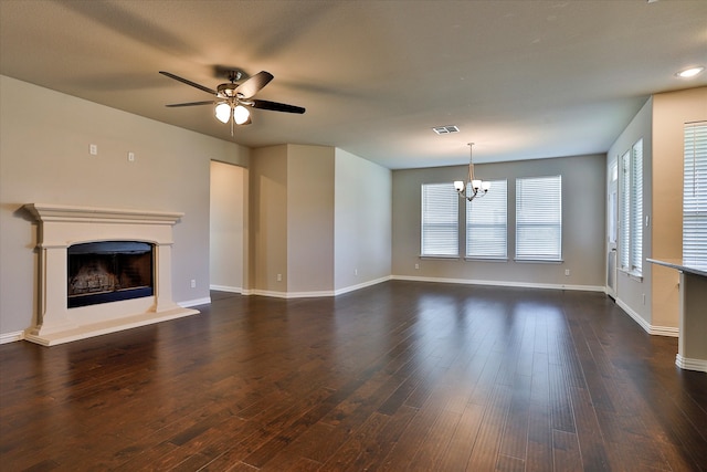 unfurnished living room with ceiling fan with notable chandelier and dark hardwood / wood-style flooring