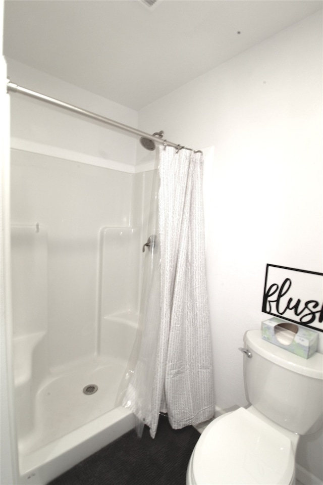 bathroom with curtained shower and toilet