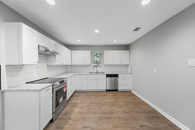 kitchen with appliances with stainless steel finishes, sink, light stone counters, light wood-type flooring, and white cabinetry