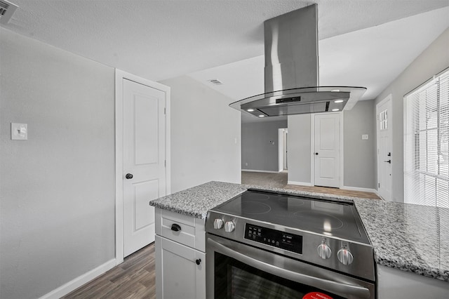 kitchen featuring island range hood, white cabinetry, stainless steel range with electric stovetop, and light stone counters