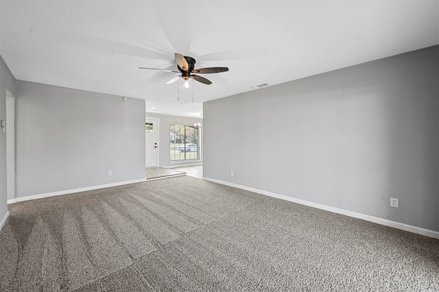 carpeted spare room featuring ceiling fan with notable chandelier