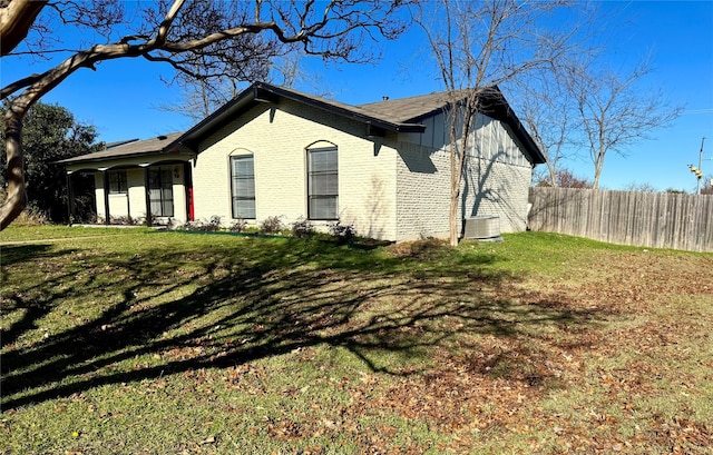 view of side of property featuring a lawn and central AC