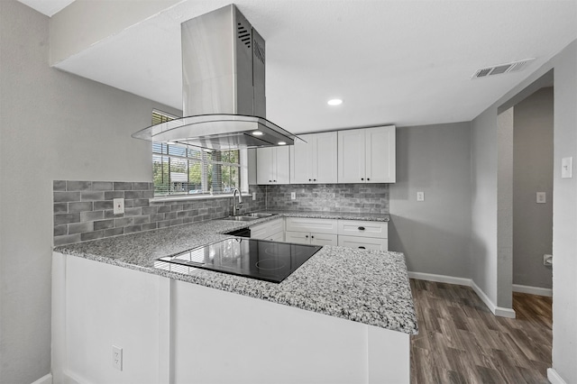 kitchen featuring white cabinetry, kitchen peninsula, island range hood, and light stone counters