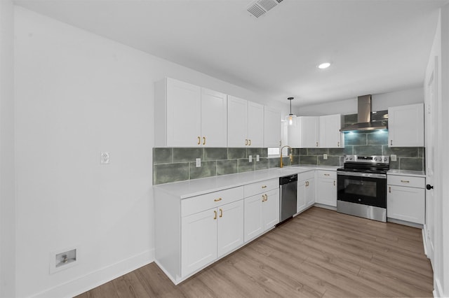 kitchen with pendant lighting, wall chimney range hood, appliances with stainless steel finishes, backsplash, and white cabinets