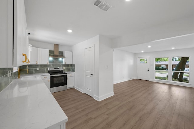 kitchen featuring white cabinetry, backsplash, light stone countertops, wall chimney range hood, and electric stove