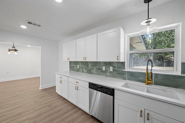 kitchen featuring pendant lighting, stainless steel dishwasher, sink, and white cabinets