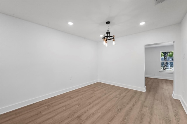 empty room featuring a chandelier and light hardwood / wood-style flooring