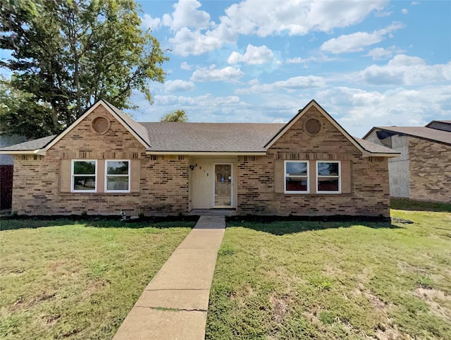 view of front of property featuring a front yard, brick siding, and roof with shingles
