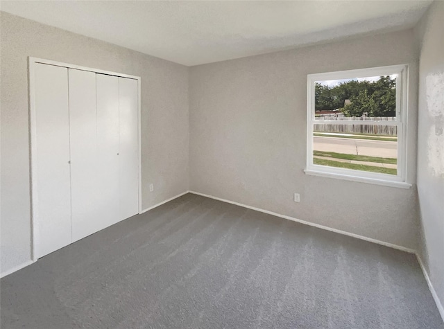 unfurnished bedroom with a closet, baseboards, and dark colored carpet