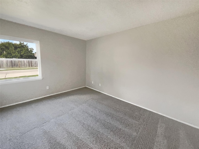 unfurnished room featuring baseboards, a textured ceiling, and dark carpet