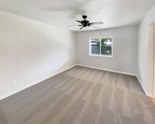 carpeted spare room with baseboards and a ceiling fan