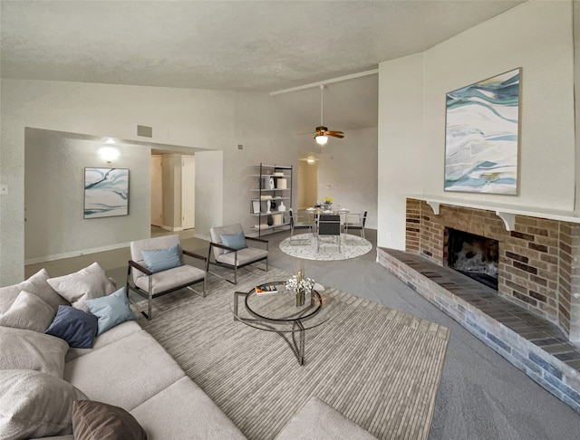 carpeted living room with vaulted ceiling, ceiling fan, a fireplace, and a textured ceiling