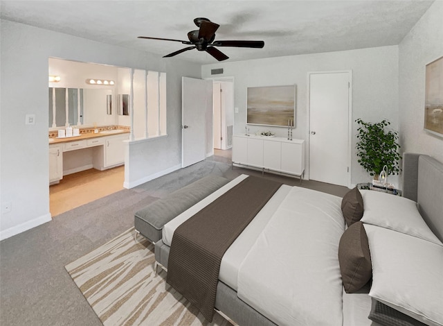 bedroom with light carpet, ensuite bath, baseboards, visible vents, and ceiling fan