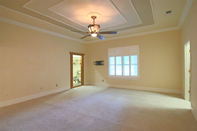 empty room featuring ceiling fan, a raised ceiling, light carpet, and ornamental molding