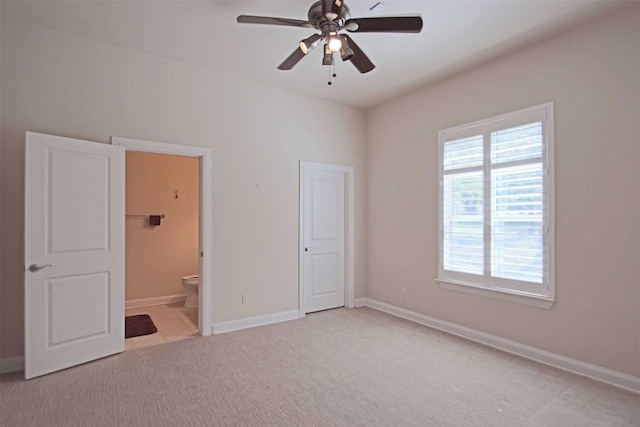 unfurnished bedroom with light carpet, connected bathroom, and ceiling fan