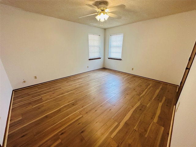 empty room featuring ceiling fan, a textured ceiling, and wood-type flooring