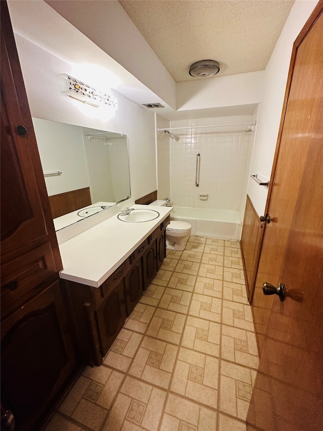 full bathroom featuring vanity, tiled shower / bath combo, toilet, and a textured ceiling