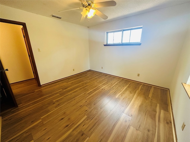 unfurnished room with wood-type flooring, ceiling fan, and a textured ceiling