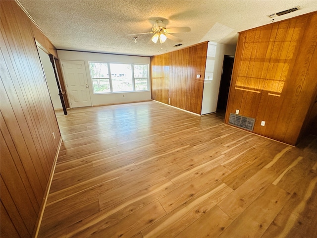 unfurnished room with light wood-type flooring, ceiling fan, and a textured ceiling