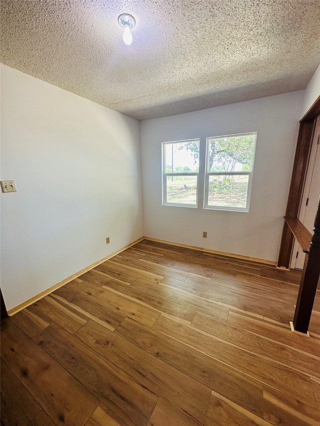 spare room with a textured ceiling and hardwood / wood-style floors