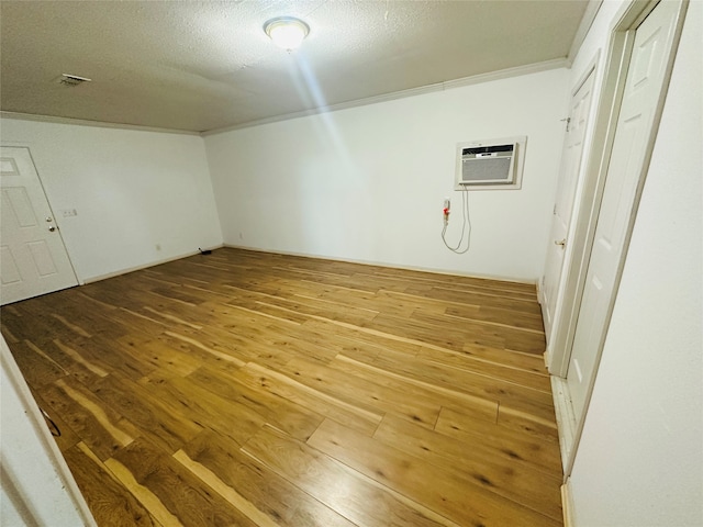 interior space featuring a textured ceiling, ornamental molding, hardwood / wood-style floors, and a wall unit AC