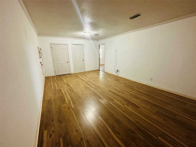 unfurnished room with a textured ceiling, hardwood / wood-style floors, and crown molding