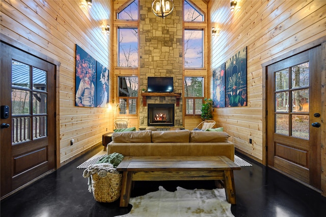 living room featuring high vaulted ceiling, a wealth of natural light, wood walls, and a fireplace