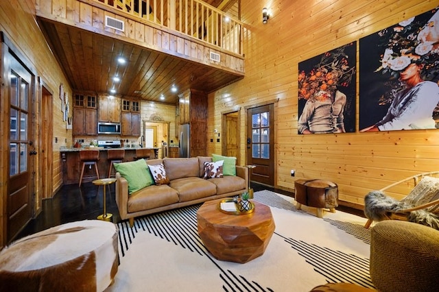 living room featuring wood ceiling, a high ceiling, and wooden walls