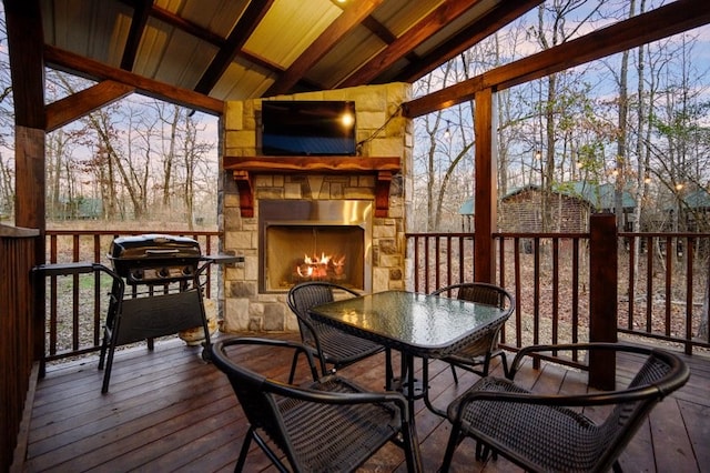 sunroom with a wealth of natural light, lofted ceiling with beams, wooden ceiling, and an outdoor stone fireplace