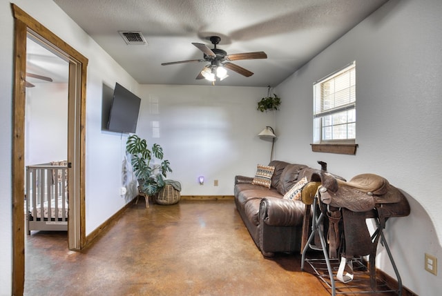 living room featuring concrete flooring, ceiling fan, and a textured ceiling