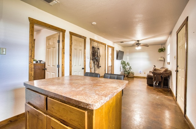 kitchen featuring a textured ceiling, a kitchen island, and ceiling fan