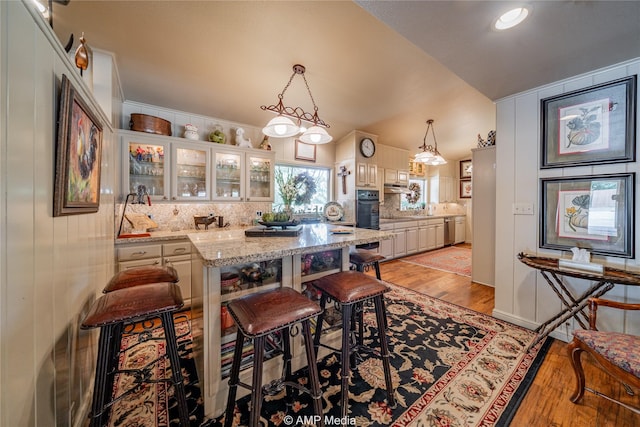 923 W Lake Dr, Hamlin, TX 79520 - kitchen featuring stainless steel dishwasher, a breakfast bar, glass insert cabinets, light wood-style floors, and backsplash