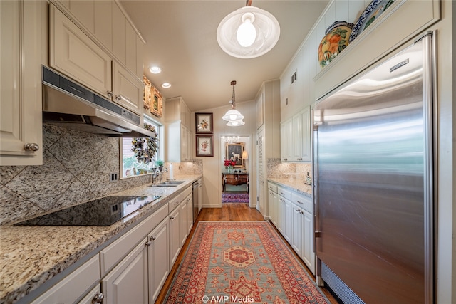 kitchen featuring stainless steel appliances, hanging light fixtures, light wood-type flooring, and tasteful backsplash