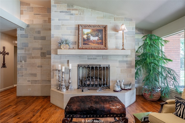 living room with hardwood / wood-style floors, vaulted ceiling, and a large fireplace