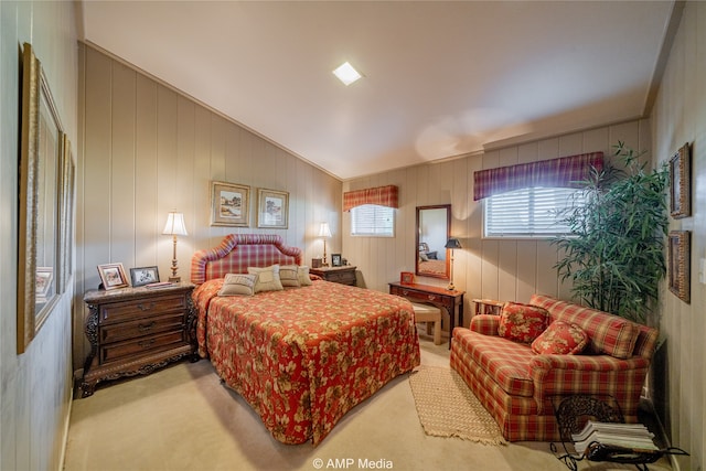 bedroom with lofted ceiling, wood walls, and light carpet