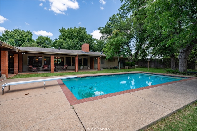 view of pool with a diving board, a yard, and a patio area