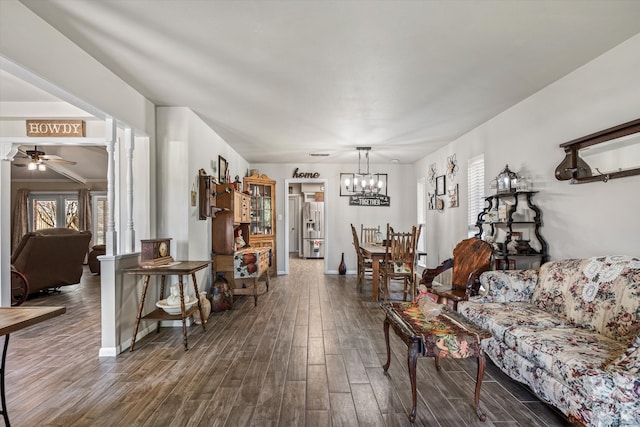 living room with ceiling fan with notable chandelier and dark wood-type flooring