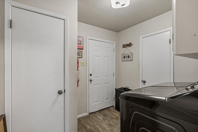 washroom featuring a textured ceiling, dark wood-type flooring, and washer and clothes dryer