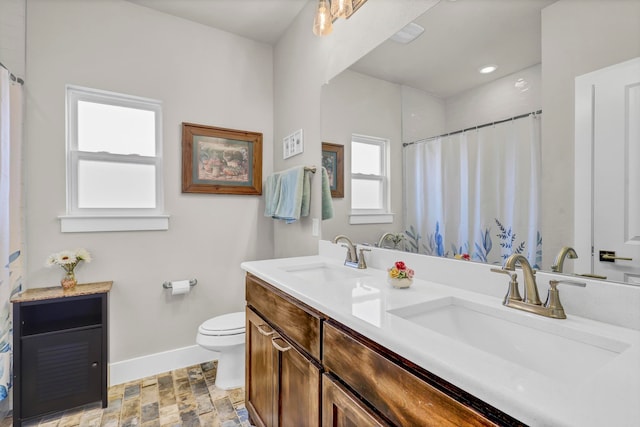 bathroom featuring a wealth of natural light, walk in shower, vanity, and toilet