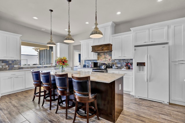 kitchen with wood-type flooring, white fridge with ice dispenser, stainless steel electric stove, and white cabinets