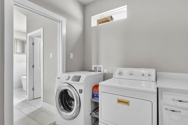 clothes washing area with washer and clothes dryer, tile walls, and light tile patterned floors