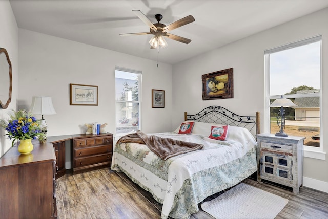 bedroom with multiple windows, wood-type flooring, and ceiling fan