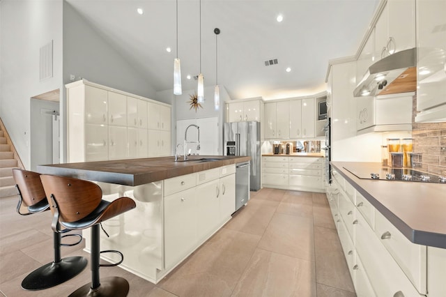 kitchen with a large island with sink, white cabinets, decorative light fixtures, stainless steel dishwasher, and sink