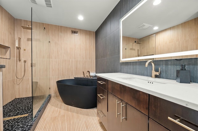 bathroom featuring independent shower and bath, vanity, tile walls, and tile patterned flooring